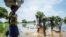 FILE - A family try to cross a flooded area after the Nile river overflowed after continuous heavy rain which caused thousands of people to be displaced in Bor, central South Sudan, Aug. 9, 2020. 