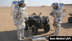 Two scientists test space suits and a device called a geo-radar for use in a future Mars mission in the Dhofar desert of southern Oman.