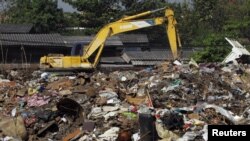 FILE - A man sifts through pile of garbage, left over after the flood, at a temporary dump site on the outskirts of Bangkok, Thailand, Dec. 20, 2011.