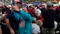 Supporters take a photo as Republican presidential nominee former President Donald Trump speaks at a campaign event at Dane Manufacturing in Waunakee, Wisconsin, Oct. 1, 2024.