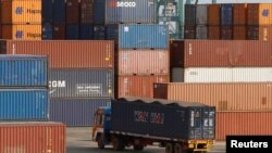 FILE - A truck ferries a shipping container at a port in the southern Indian city of Chennai, Feb. 13, 2013.
