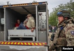 A police officer helps local residents during an evacuation to Kharkiv due to Russian shelling near the town of Vovchansk on May 17, 2024.