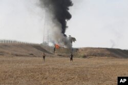 Palestinci stoje ispred osmatračnice izraelske vojske u pojasu Gaze. (Foto: AP/Hatem Ali)