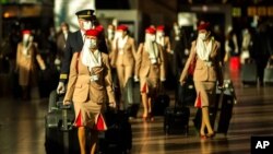 FILE - Cabin crew members, wearing face masks to prevent the spread of the coronavirus, walk along the departure hall of the Zaventem international airport in Brussels, Jan. 22, 2021. 