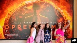 From left, Gabrielle Roitman, Kayla Seffing, Maddy Hiller and Casey Myer take a selfie in front of an "Oppenheimer" movie poster before they attended an advance screening of "Barbie," July 20, 2023, at AMC The Grove 14 theaters in Los Angeles.