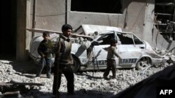 Syrian children walk through the debris in the rebel-held area of Douma, east of the capital Damascus, following reported airstrikes by regime forces, March 13, 2015. 