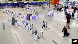 FILE - Travelers walk through the nearly empty JetBlue terminal at Logan Airport on Nov. 20, 2020, in Boston, Massachusetts. (AP Photo/Michael Dwyer)