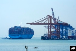 រូបឯកសារ៖ បុរសម្នាក់​ជិះទូកនេសាទ ខណៈ​នាវា​ដឹក​ទំនិញ​ត្រៀមសំចត​នៅ​កំពង់ផែ​ ក្នុង​ក្រុង Xiamen នៃខេត្ត Fujian ប្រទេស​ចិន កាលពីថ្ងៃទី២៧ ខែធ្នូ ឆ្នាំ២០២៣។