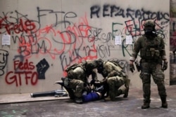 FILE - Federal law enforcement officers detain a protester during a demonstration against the presence of federal law enforcement officers and racial inequality in Portland, Oregon, July 21, 2020.