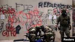 FILE - Federal law enforcement officers detain a protester during a demonstration against the presence of federal law enforcement officers and racial inequality in Portland, Oregon, July 21, 2020. 