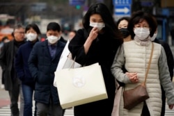Pedestrians wearing masks to prevent contracting the coronavirus walk on a zebra crossing in Seoul, South Korea, March 12, 2020.
