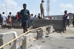 A protester carriying a stick walks past barricades mounted on the Lagos-Ibadan expressway to protest against police brutality and the killing of protesters by the military, at Magboro, Ogun State, Oct. 21, 2020. (AFP)