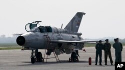 FILE - A ground crew stands on the tarmac by a MiG-21 fighter jet at the military airport Batajnica, near Belgrade, Serbia, April 6, 2016. Serbia has recently procured six MiG-29 jets, 30 tanks and armored personnel carriers from Russia.