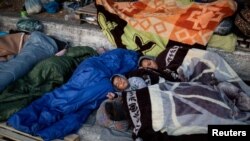 Pengungsi dan migran dari kamp Moria beristirahat di pinggir jalan pulau Lesbos, Yunani, 13 September 2020. 