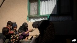 Mina Ahmed, center, is helped by her children in Salar village, Wardak province, Afghanistan, Oct. 24, 2021.