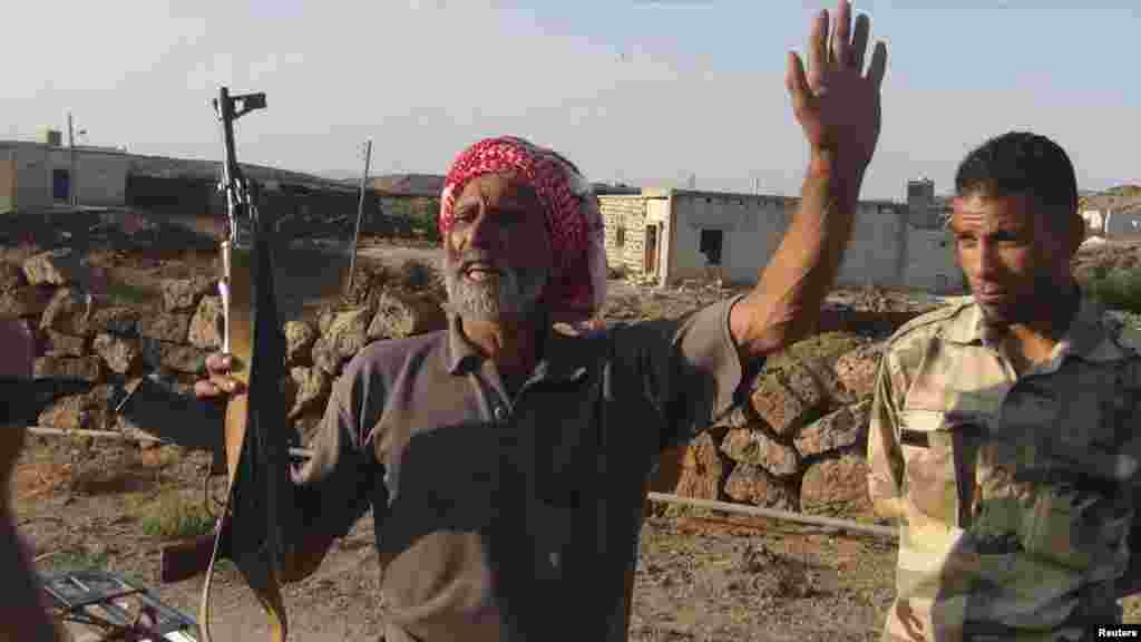 A resident holds a rifle next to a member of the Free Syrian Army at Al-Lujat, near Dara, October 7, 2012. 
