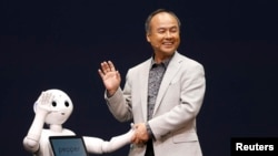 CEO SoftBank Corp. Masayoshi Son (R) dengan robot bernama Pepper produksi perusahaannya dalam konferensi pers di Urayasu, timur Tokyo. 