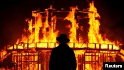 A visitor to Burning Man watches an art burn