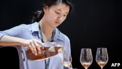 Picture taken on May 27, 2014 shows a woman pouring a glass of cognac at Vinexpo Asia Pacific in Hong Kong. 