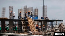 FILE - Construction laborers work at a building site in Bangkok, June 18, 2014.