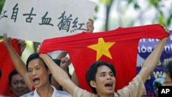 A protester holds a red T-shirt with a yellow star, representing Vietnam's national flag, while chanting anti-China slogans with other demonstrators during a rally against China's claims in the oil-rich South China Sea, in Hanoi, Vietnam, July 2011. (file