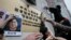 FILE - Protesters try to stick photos of missing booksellers, one of which shows Gui Minhai, at left, during a protest outside the Liaison of the Central People's Government in Hong Kong, Jan. 3, 2016. 