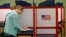 FILE - A woman casts marks her ballot during primary voting in Durham, N.C., May 8, 2018. 
