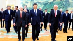In this photo released by Xinhua News Agency, Chinese President Xi Jinping, center, walks with representatives from U.S. business, strategic and academic concerns at the Great Hall of the People in Beijing, March 27, 2024.