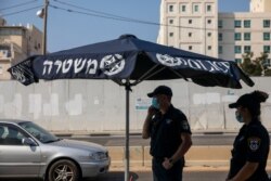 Israeli police officers wearing face masks to protect against coronavirus secure a check point on the first day of three-week lockdown in Bnei Brak, Israel, Sept 18, 2020.