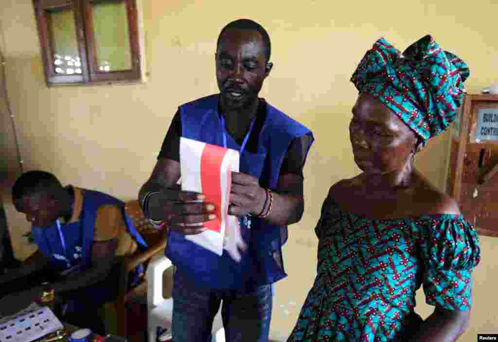 An election official shows to a woman how to cast her ballot during Liberia&#39;s presidential election in Monrovia, Oct. 10, 2017.