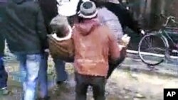 This image made from amateur video and released December 27, 2011, purports to show men carrying an injured man in Homs, Syria, December 26, 2011.