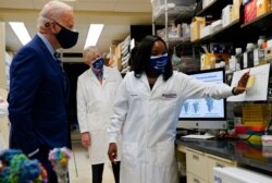 President Joe Biden listens as Kizzmekia Corbett, an immunologist with the Vaccine Research Center at the National Institutes of Health, speaks during a visit at the NIH Feb. 11, 2021, in Bethesda, Md. NIH Director Francis Collins is at center.
