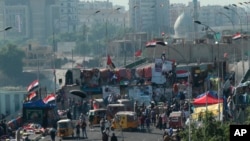 Pengunjuk rasa melakukan aksi duduk di Jembatan Sinak sementara pasukan keamanan berjaga di balik tembok beton, di Baghdad, Irak, Kamis, 21 November 2019. 