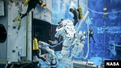 FILE - Astronauts practice on a Hubble model underwater at the Neutral Buoyancy Lab in Houston under the watchful eyes of NASA engineers and safety divers. China aims to build a deep-sea lab that provides long-time living and working space for scientists.