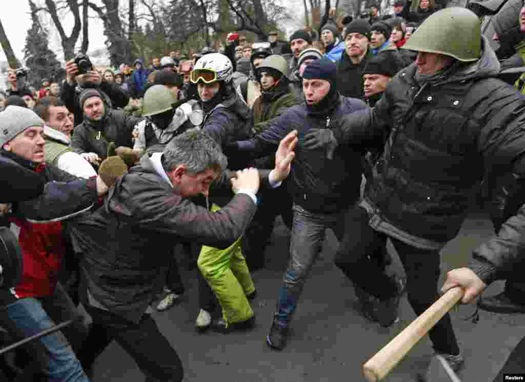 Anti-government protesters attack a deputy of the Party of Regions Vitaly Grushevsky (2nd L, front) outside the Ukrainian Parliament building in Kyiv.