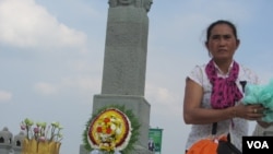 ស្រ្តី⁣ម្នាក់នៅក្បែរស្តូប​អនុស្សាវរីយ៍​មួយ​នៅ​ក្បែរ​ស្ពាន​ពេជ្រ​។​ ហេង រស្មី