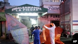 Workers at an embalming facility in Mexico City prepare to unload a truck containing dozens of the 145 bodies found in mass graves in northern Mexico, April 14, 2011