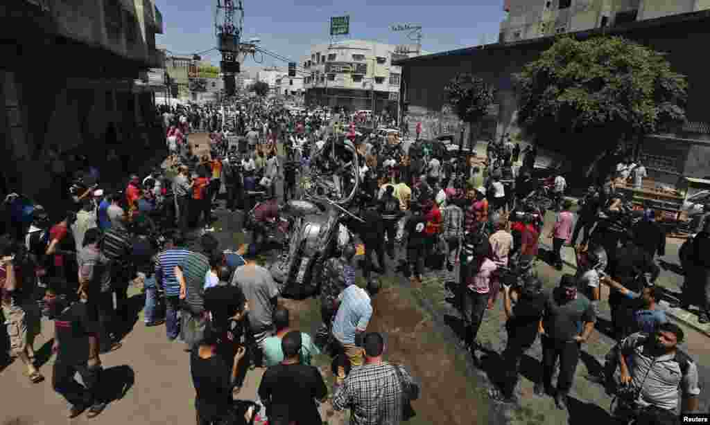 Falastinliklar Isroil havo hujumida nishonga olingan va vayron qilingan mashina qoldiqlarini ko&#39;zdan kechirmoqda, G&#39;azo, 8-iyul, 2014-yil.