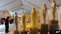 A worker stands next to the Oscar statues during a preparation work for the upcoming OSCARS, the 85th Academy Awards, at Hollywood Boulevard in Hollywood, California, February 19, 2013.