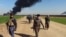 FILE - Members of the Kurdish Peshmerga forces and the Iraqi security forces patrol on a road as smoke billows from the Khubbaz oil field, some 25 km west of the northern city of Kirkuk, Feb. 2, 2015. 