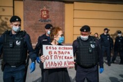Police officers detain Russian photographer Victoria Ivleva, center, during a solo picket in support of journalist and activist Ilya Azar outside the Moscow police headquarters in Moscow, May 28, 2020.