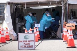 FILE - A medical worker administers a test for a COVID-19 at a facility in Camden, N.J., April 1, 2020.
