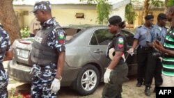 Policemen stand at the scene of a bomb blast at the public health college in northern Nigerian city of Kano, June 23, 2014.