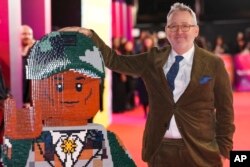 Sutradara Morgan Neville dengan figur lego Pharrell Williams, di pemutaran film 'Piece by Piece' di London (Scott A Garfitt/Invision/AP)