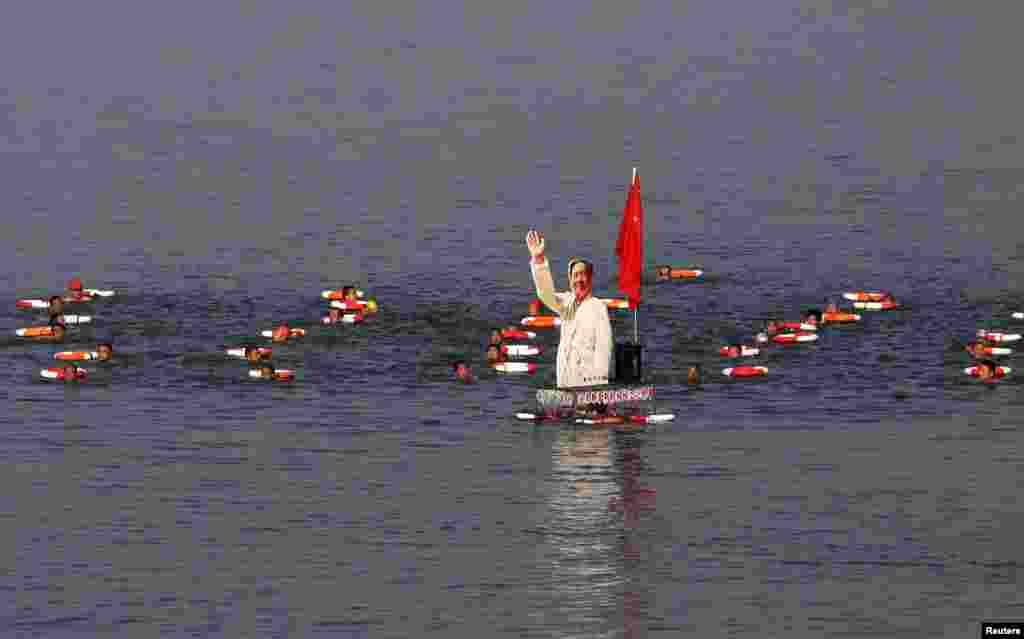 Para peserta lomba renang berenang dengan gambar tokoh China mendiang Mao Zedong si sungai Hanjiang, cabang sungai Yangtze, di Xiangyang, China.