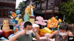 Visitors to the Yu Garden Mall put their masks on after posing for photos, June 2, 2022, in Shanghai. 