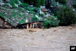 Aliran air Sungai Yellowstone yang deras membanjiri tempat yang tampak seperti gudang perahu kecil di Gardiner, Montana, tepat di utara Taman Nasional Yellowstone, Senin, 13 Juni 2022. (Sam Glotzbach melalui AP)