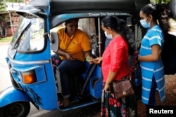 A passenger pays Lasanda Deepthi, 43, an auto-rickshaw driver for local ride hailing app PickMe, after they got dropped off at their destination in Gonapola town, on the outskirts of Colombo, Sri Lanka, May 25, 2022. (REUTERS/Adnan Abidi )