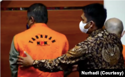 Petugas KPK mengarahkan posisi berdiri seorang tersangka koruptor di Gedung Merah Putih KPK.