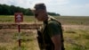 A Ukrainian soldier walks near a post warning about landmines in a field on the outskirts of Kyiv, June 9, 2022.